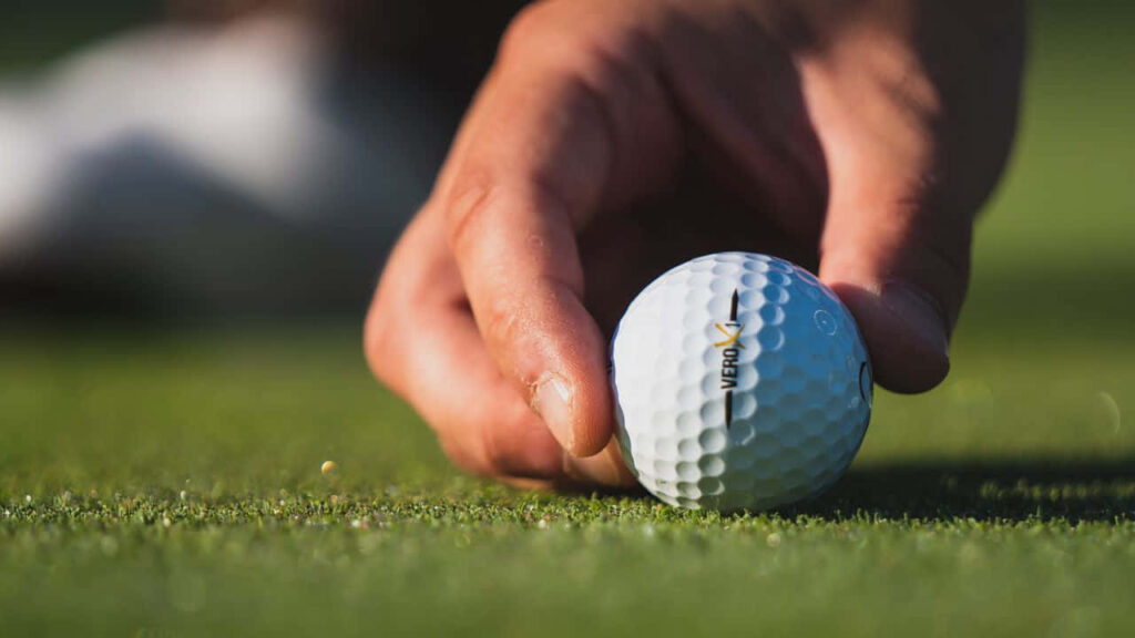 Golf Wallpaper: Close-Up Hand Placing Ball on Green - Precision Focus
