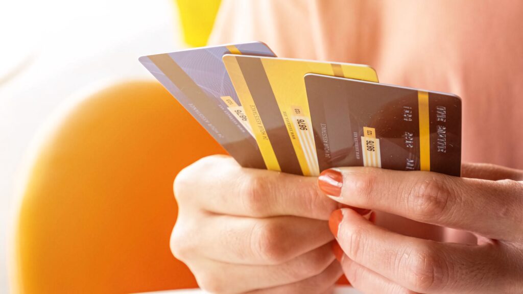Hand holding colorful credit cards on warm background finance banking lifestyle wallpaper