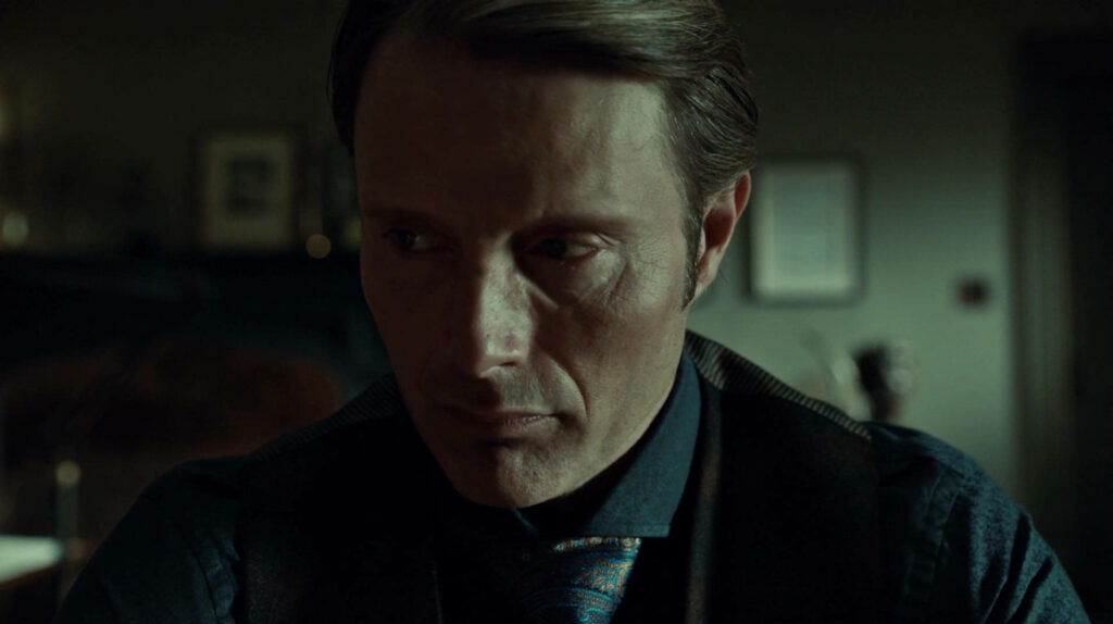 Hannibal Close-Up Wallpaper: Intense Expression in Dim Light