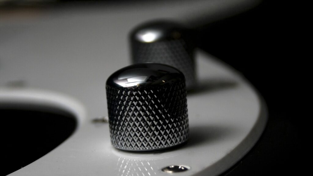 Close-Up of Textured Metallic Guitar Knob on Minimalist Wallpaper