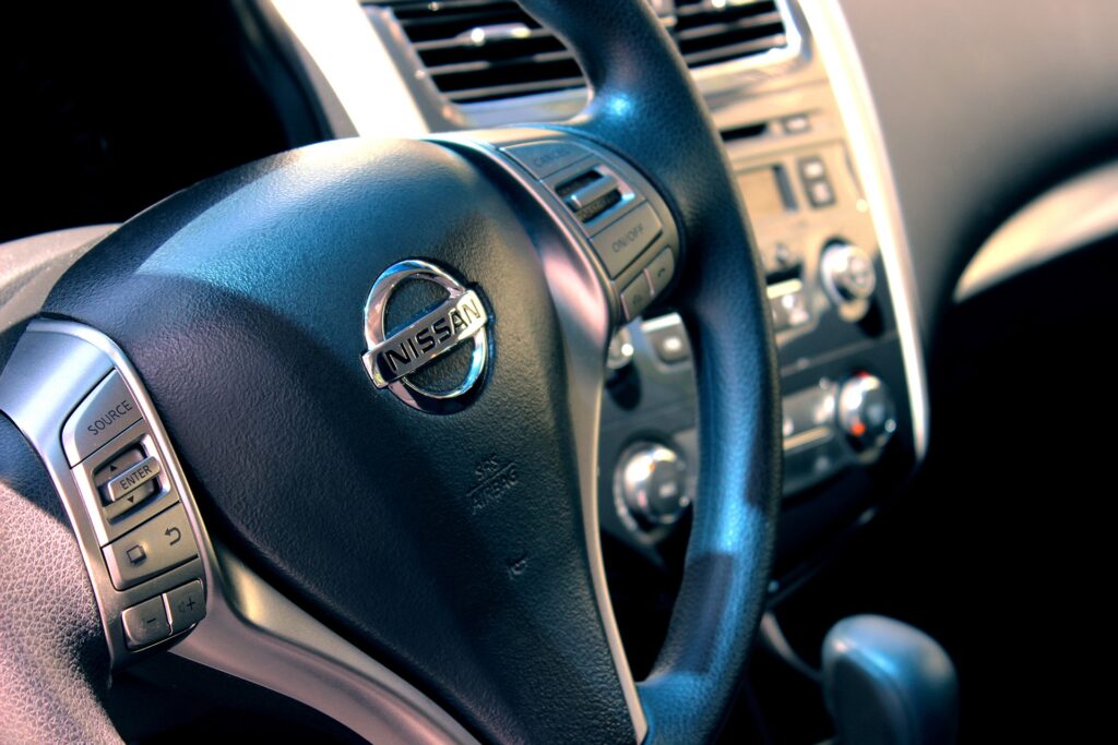 Close-Up Nissan Car Interior: Modern Steering Wheel & Logo Design Wallpaper