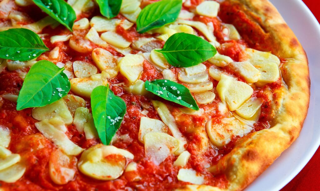 Delicious Pizza Close-Up with Basil, Garlic, & Tomato Sauce Wallpaper
