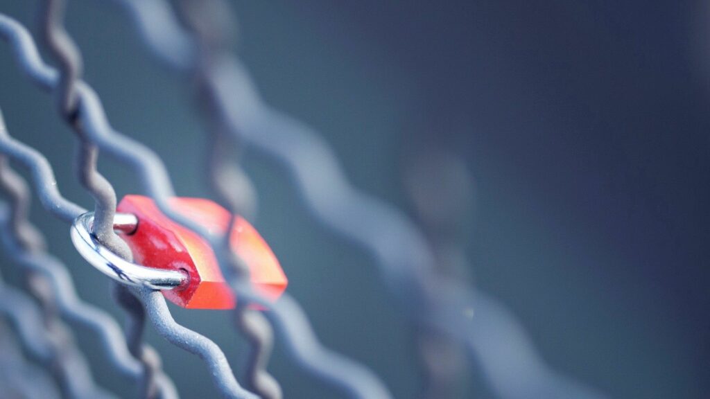 Red Lock on Metal Fence: Soft Motion Blur Wallpaper Background