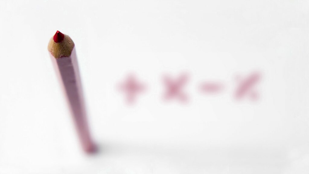 Sharp Red Pencil Wallpaper: Close-Up with Blurred Math Symbols