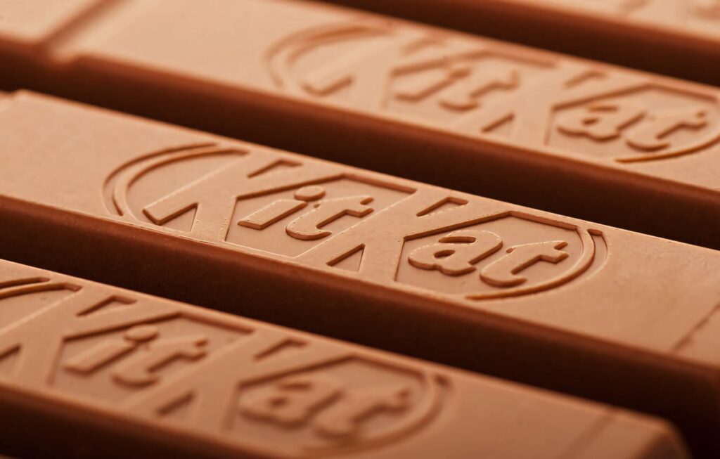 Close-up of smooth milk chocolate Kit Kat bars with embossed logo and rich brown tones background Wallpaper