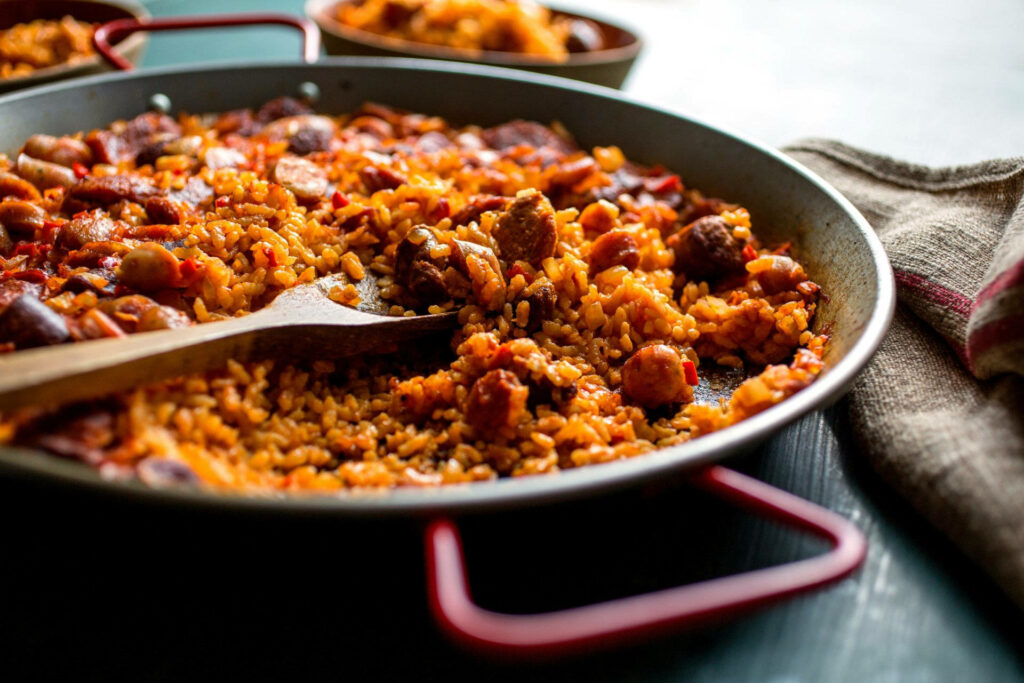 Vibrant Paella Close-Up: Savory Rice & Meats in Traditional Pan Wallpaper