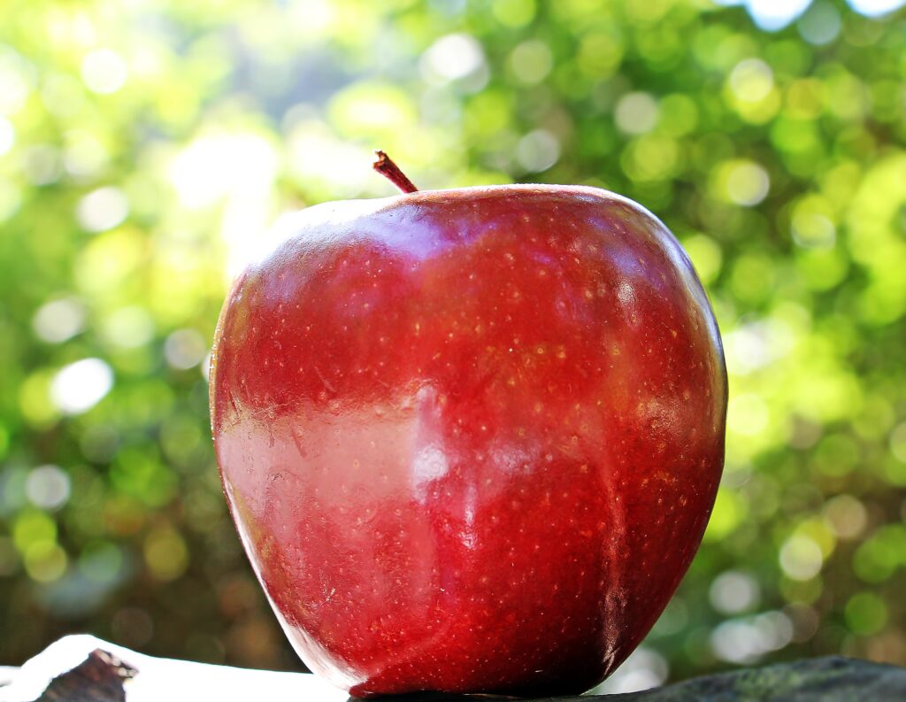 Vibrant Red Apple Wallpaper: Glossy Close-Up with Natural Background