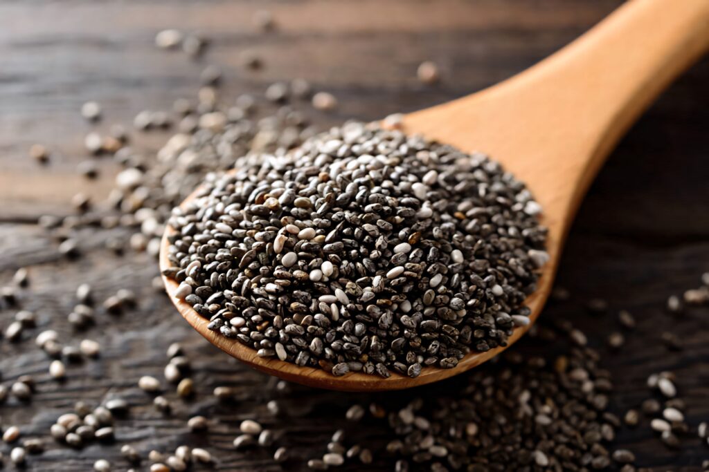 Close-up of wooden spoon filled with black and white chia seeds on rustic wood background Wallpaper