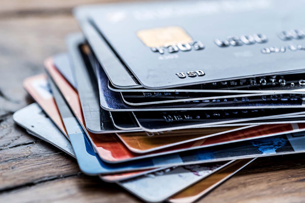 Close-up of assorted credit cards stacked on rustic wood highlighting finance and consumerism Wallpaper