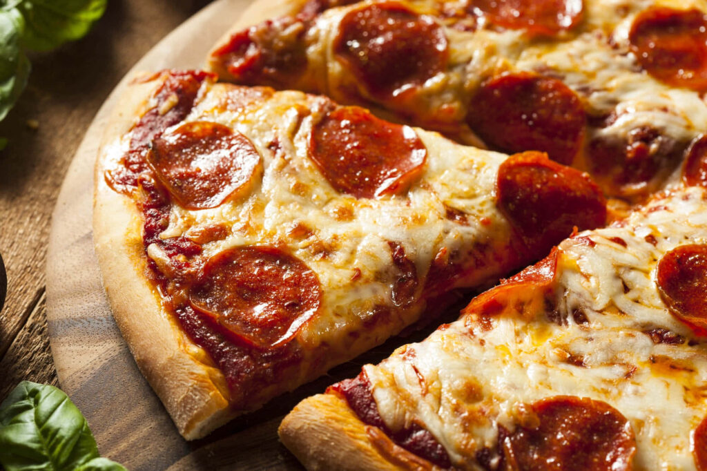 Close-up of a slice of pepperoni pizza with melted cheese on a crispy golden crust wallpaper background