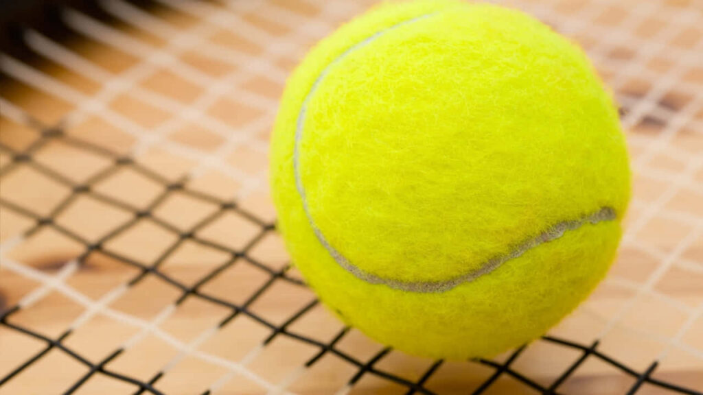 Vibrant Yellow Tennis Ball Close-Up on Racket - Wallpaper Background