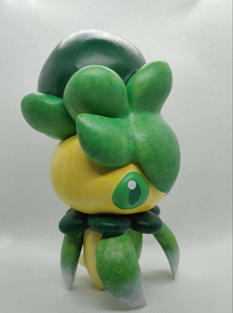 Close-up of 3D-printed Fomantis figurine with green yellow paint on white background gaming wallpaper