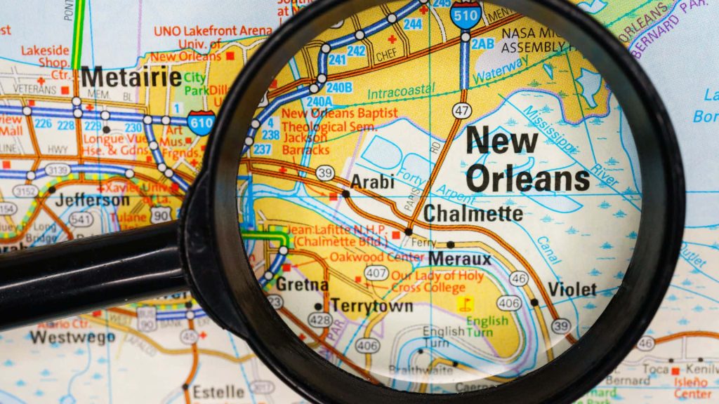 Close-up of black-rimmed magnifying glass on vibrant New Orleans map highlighting landmarks Wallpaper