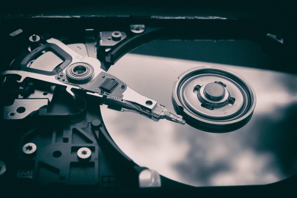Close-up of open hard drive read write head and polished platter in cool tones wallpaper background