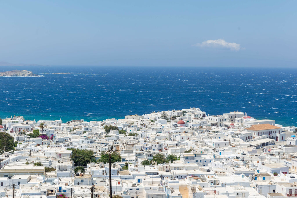 Coastal cityscape with white buildings by deep blue sea under bright sky vibrant wallpaper background