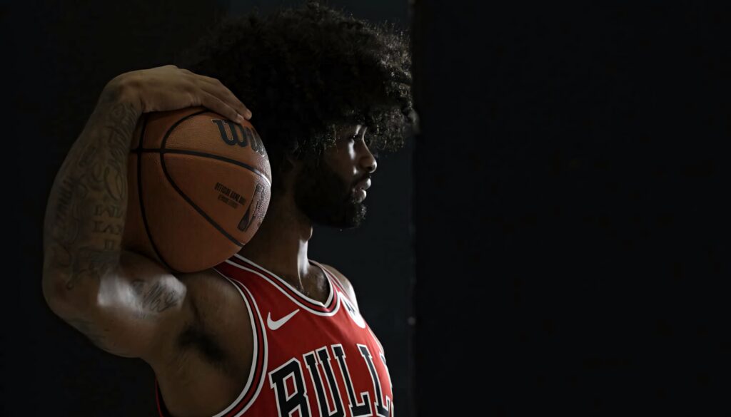 Coby White in Chicago Bulls jersey holding basketball dramatic sports portrait with dark background Wallpaper