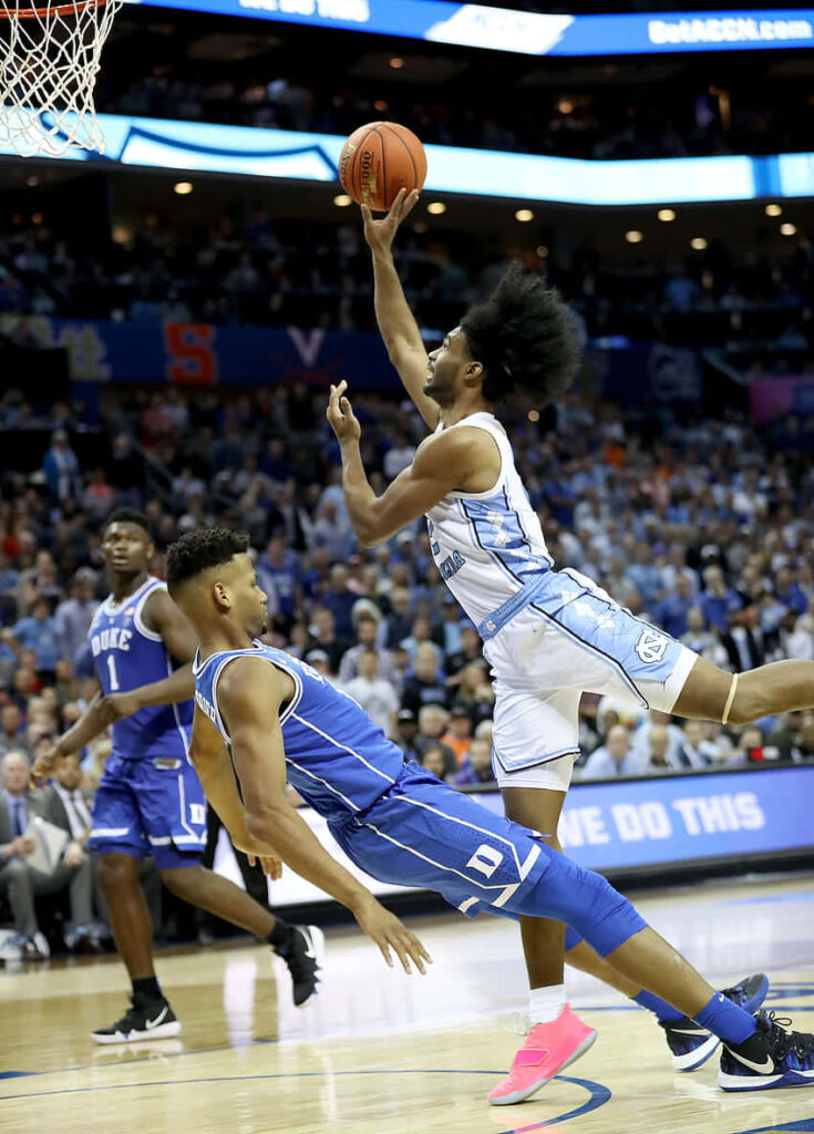 Coby White mid-air layup driving past Duke defender intense college basketball game action Wallpaper