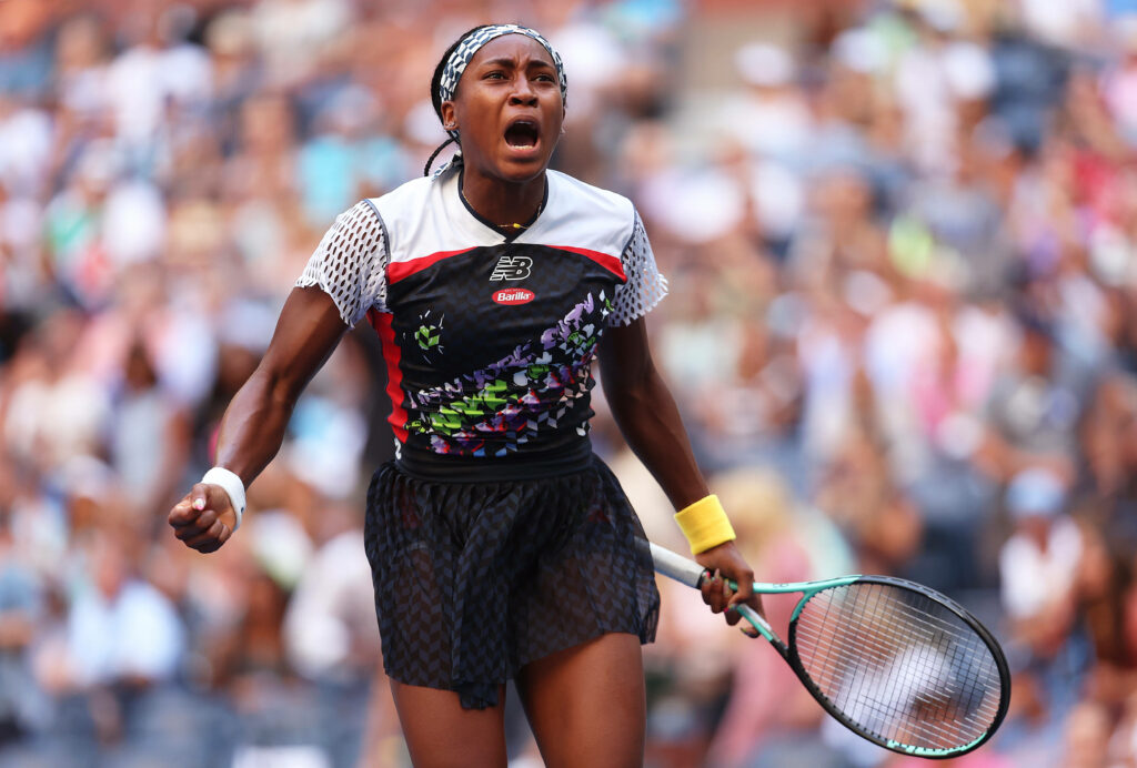 Coco Gauff in vibrant floral tennis outfit lunging during intense match with expressive emotion Wallpaper