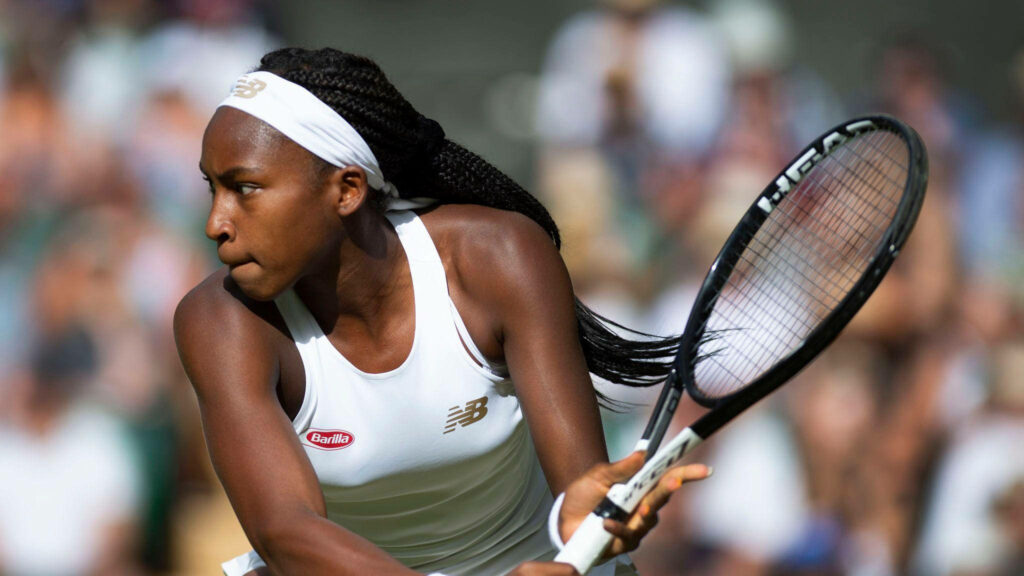 Coco Gauff mid-match focused in white tennis outfit gripping racket dynamic professional tennis Wallpaper