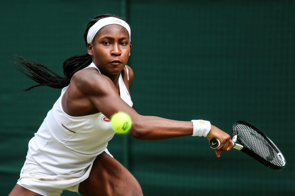 Coco Gauff intense tennis action powerful return vivid detailed green court wallpaper background