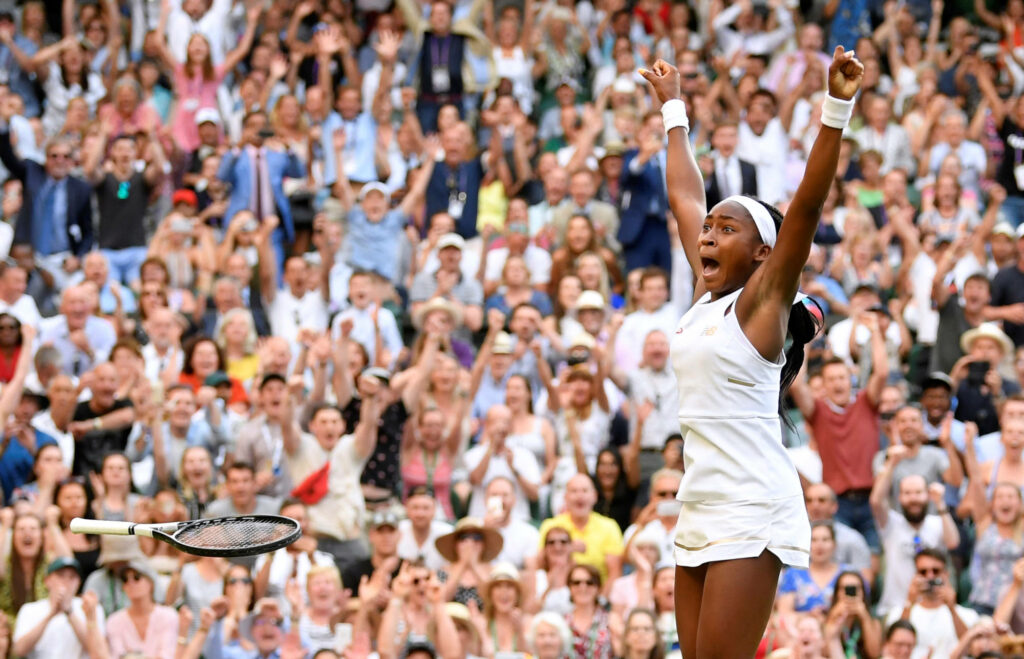 Coco Gauff celebrates tennis victory in white outfit with excited crowd in dynamic court action Wallpaper