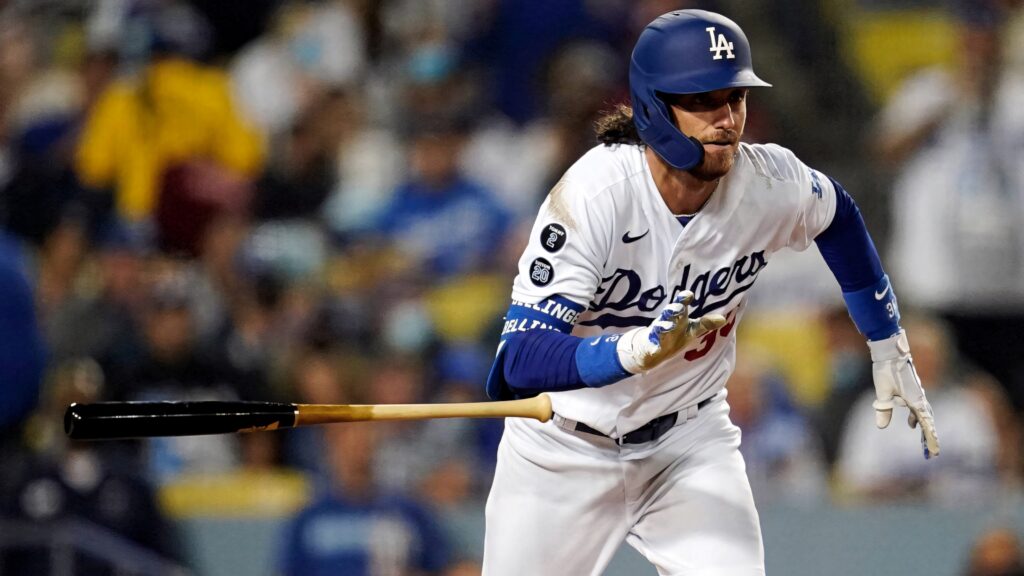 Cody Bellinger running energetically after hitting the ball in Dodgers game with blurred stadium background Wallpaper