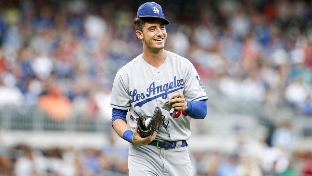 Cody Bellinger in Los Angeles Dodgers uniform smiling on baseball field with glove and stadium crowd Wallpaper