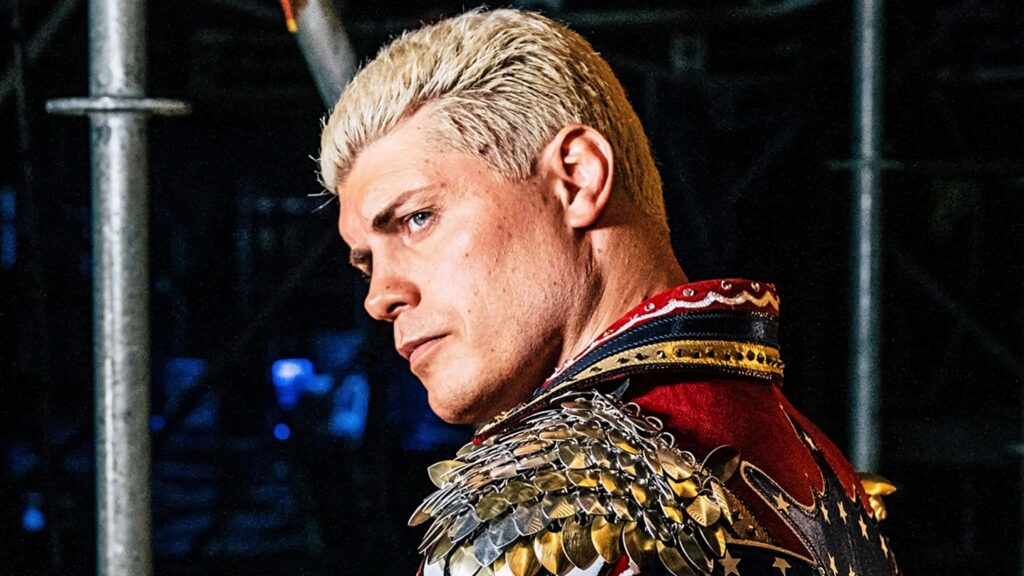 Cody Rhodes side view platinum blond hair gold studded jacket dark industrial WWE background Wallpaper