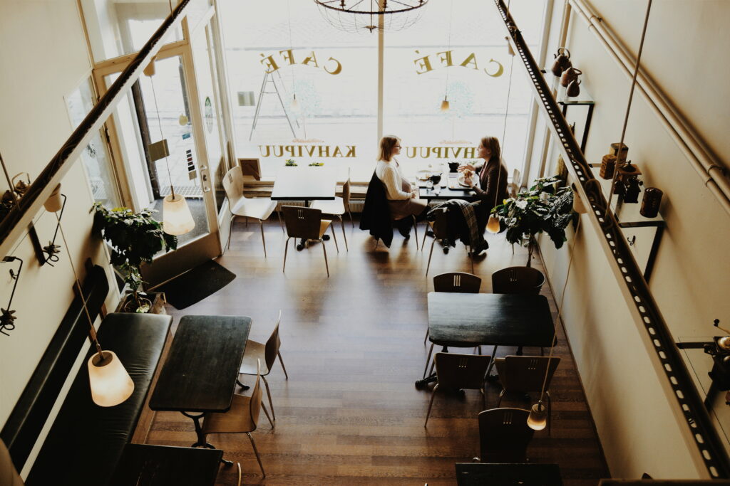 Coffee Break Conversations: A Snapshot of Sisterly Chatter against a Chic Café Wallpaper