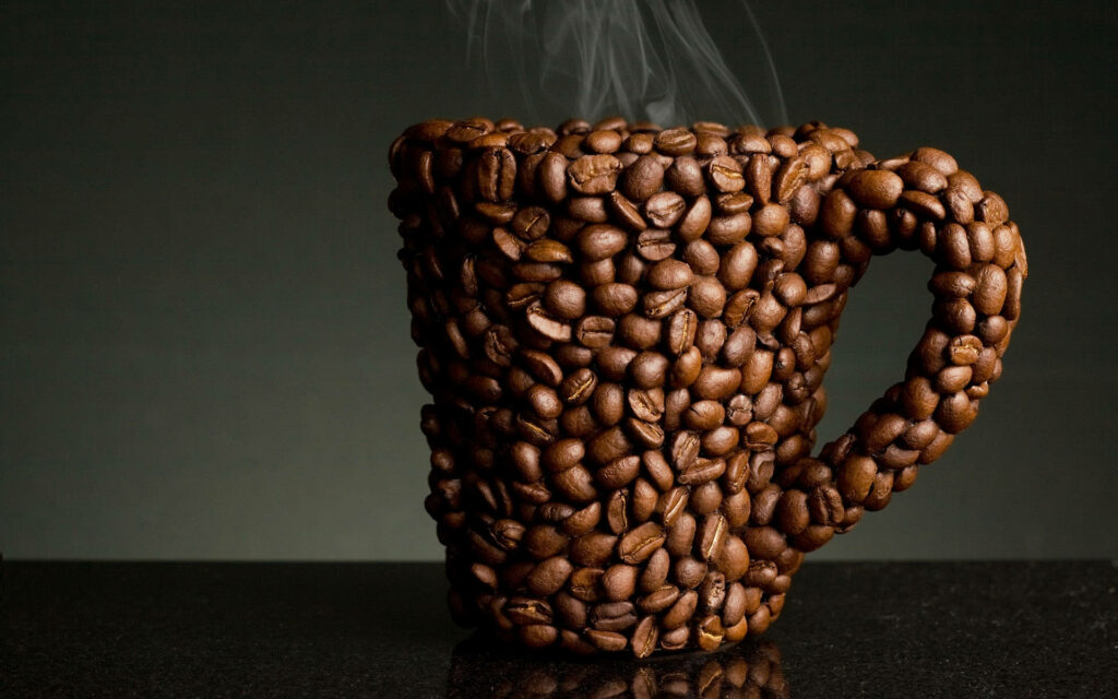 Coffee cup made of brown coffee beans with steam on dark minimalist artistic wallpaper background