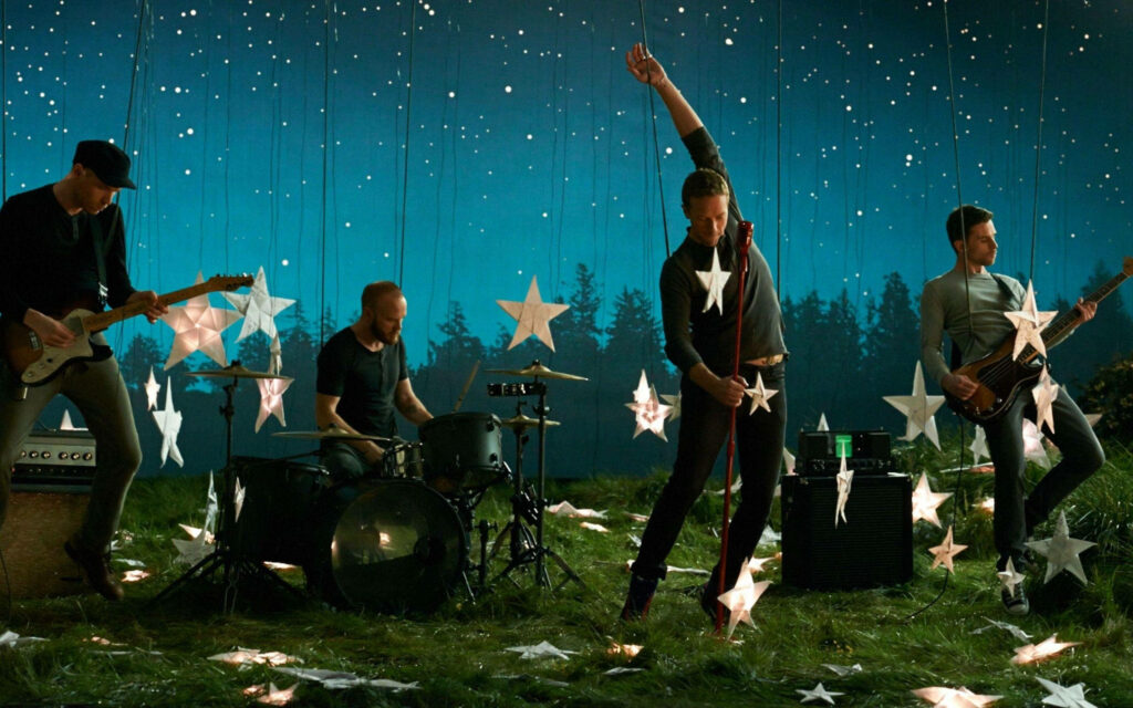 Coldplay performing under starry night sky inspired by A Sky Full Of Stars wallpaper background