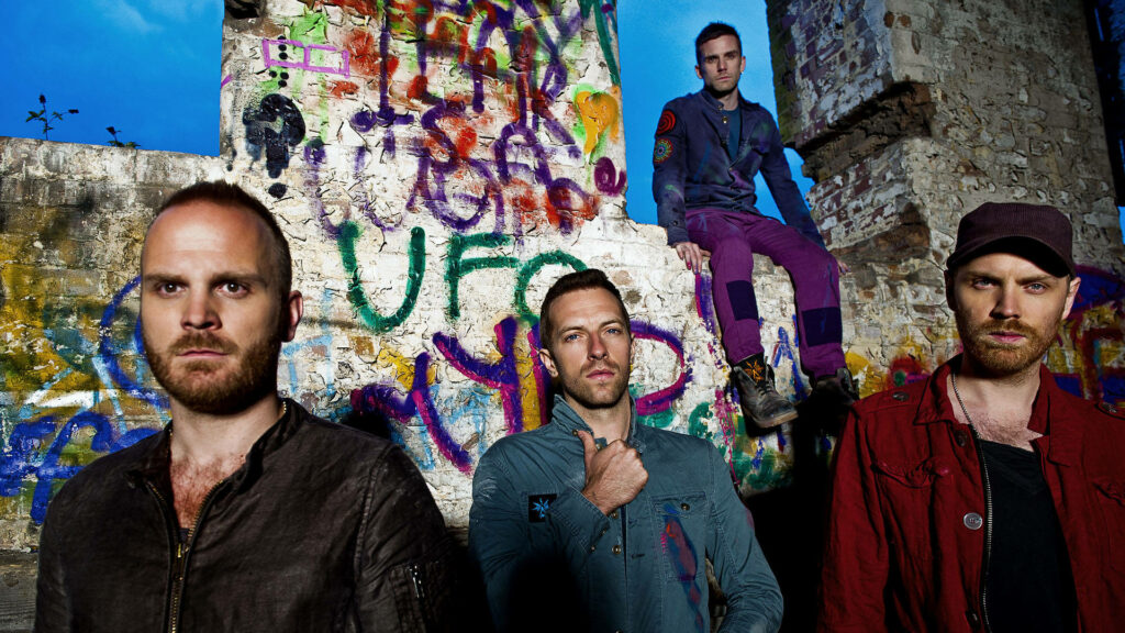 Coldplay band members stand before vibrant colorful graffiti wall urban artistic wallpaper background