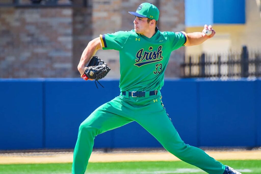 Cole Kmet pitching on baseball field in vibrant green Irish uniform dynamic athletic action wallpaper