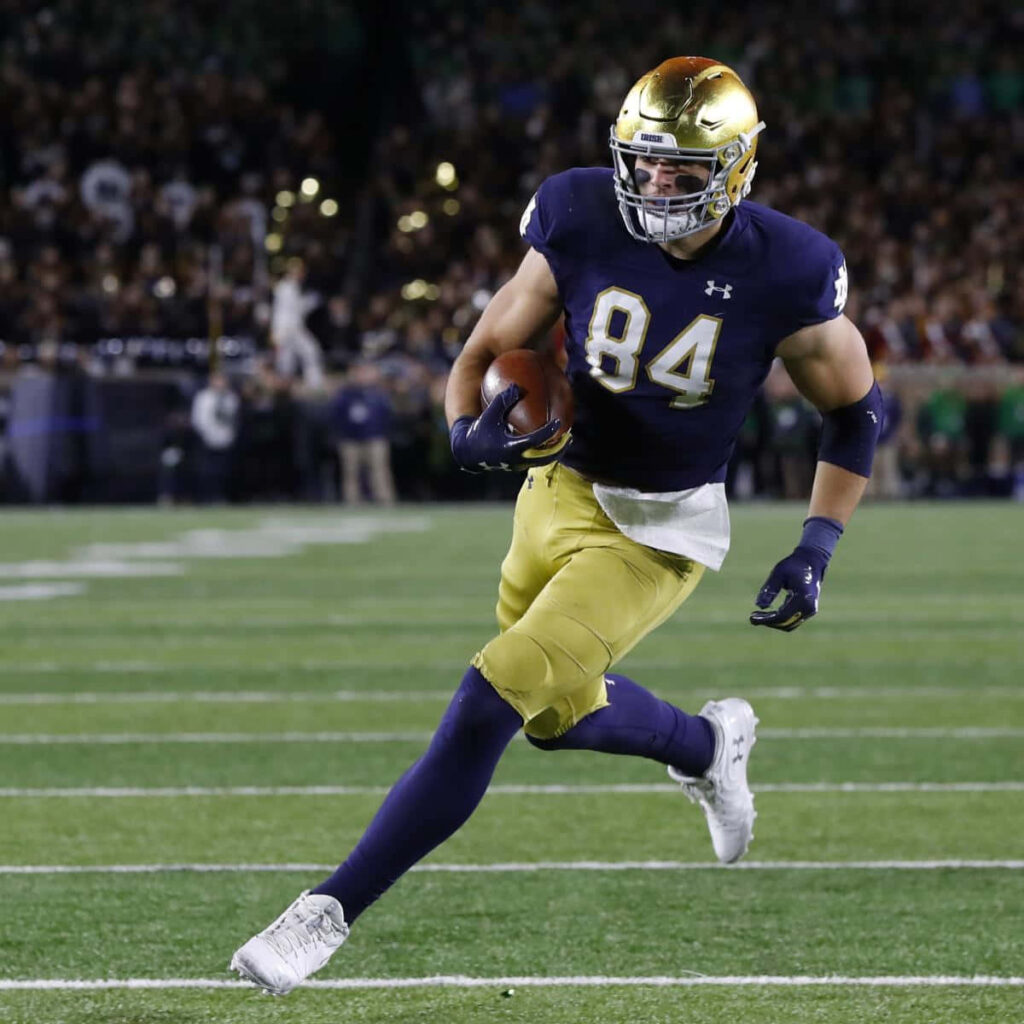 Cole Kmet Notre Dame football player number 84 in action showing athleticism and focus under stadium lights Wallpaper