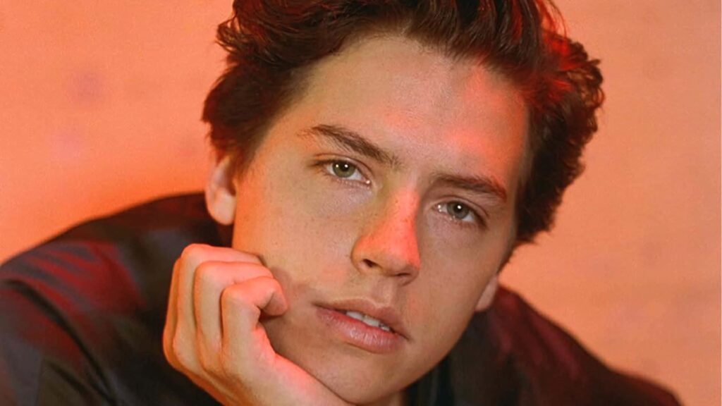 Close-up portrait of Cole Sprouse with warm lighting and orange background wallpaper design
