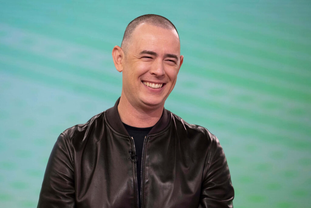 Colin Hanks smiling in black leather jacket against soft green modern background wallpaper