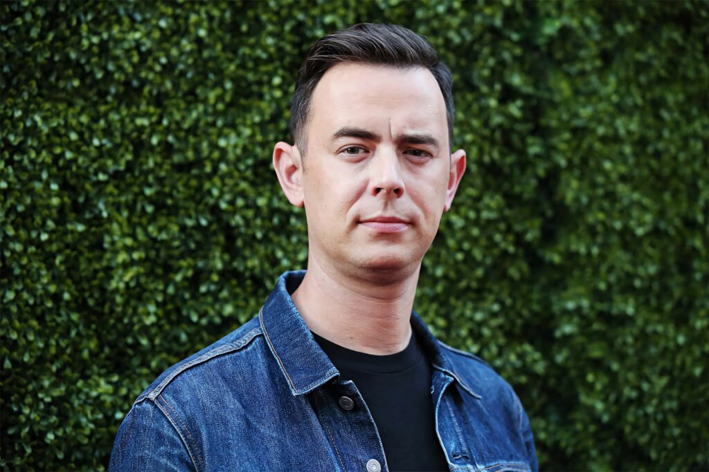 Colin Hanks in dark denim jacket and black shirt against green background natural light portrait Wallpaper