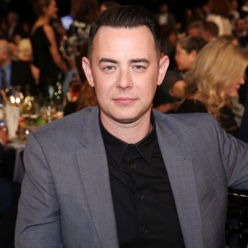 Colin Hanks in sharp gray suit and black shirt at formal event with elegant blurred background Wallpaper