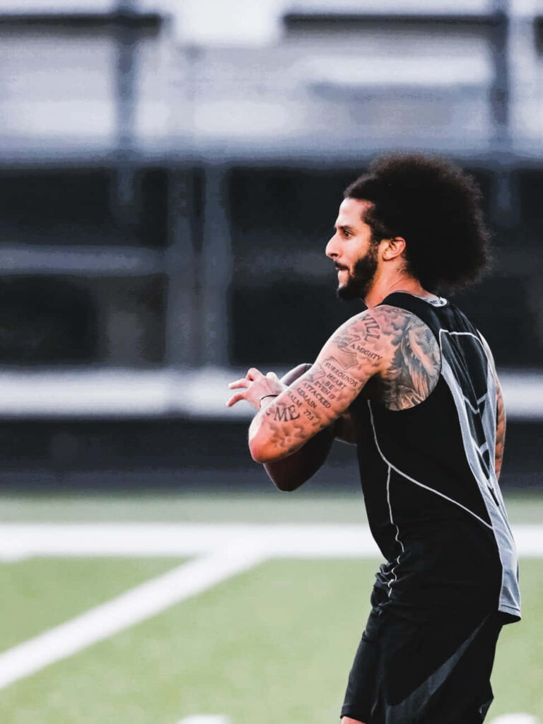 Colin Kaepernick football wallpaper showing his tattoos and athletic build preparing to throw