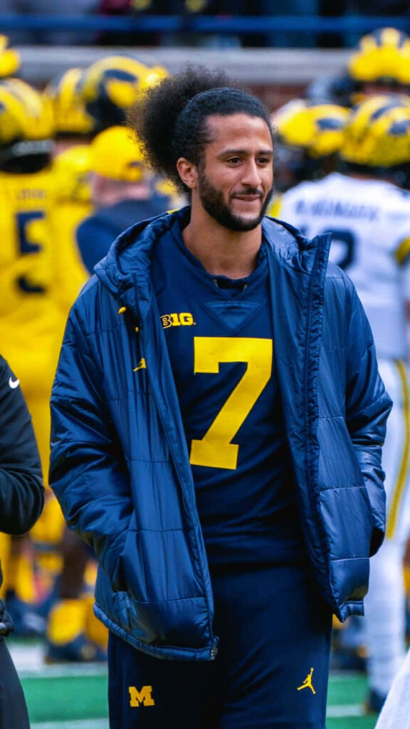 Colin Kaepernick in navy Michigan Wolverines jacket with teammates in yellow helmets football wallpaper