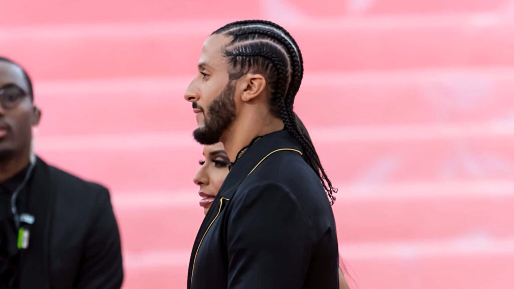 Colin Kaepernick profile portrait braided hair serious expression modern minimalist style pink background Wallpaper