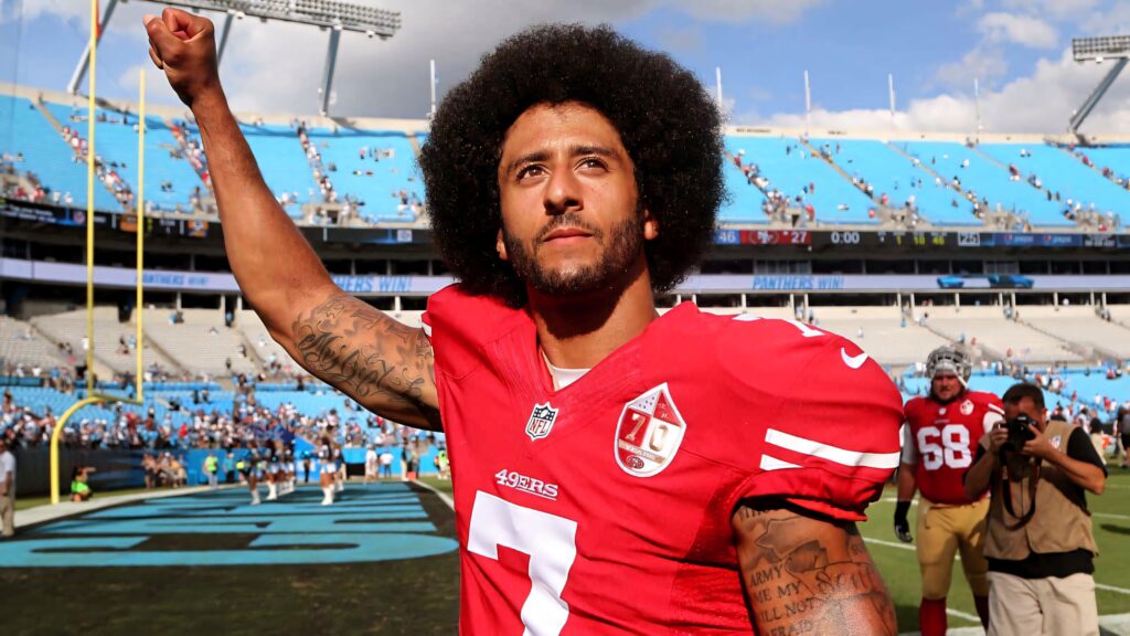 Colin Kaepernick raising fist on football field in red jersey showing strength activism athleticism Wallpaper