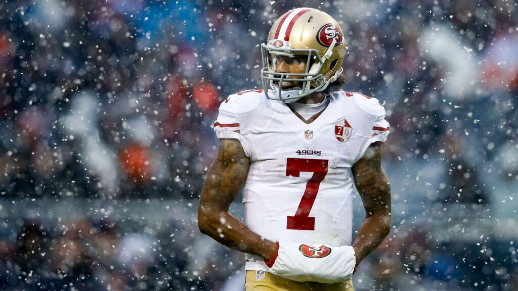 Colin Kaepernick in red gold San Francisco 49ers uniform number 7 on snowy football field Wallpaper