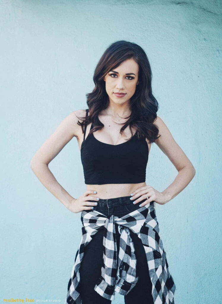 Colleen Ballinger confident in black crop top plaid shirt tied high-waisted pants blue background Wallpaper