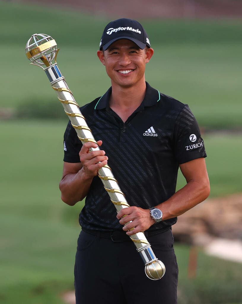 Collin Morikawa smiling on golf course holding golden trophy in black Adidas TaylorMade outfit Wallpaper