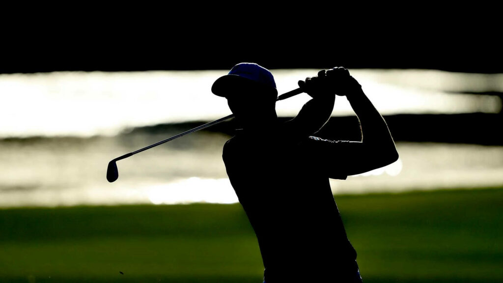 Collin Morikawa silhouette mid-swing golf wallpaper with glowing water and lush green background