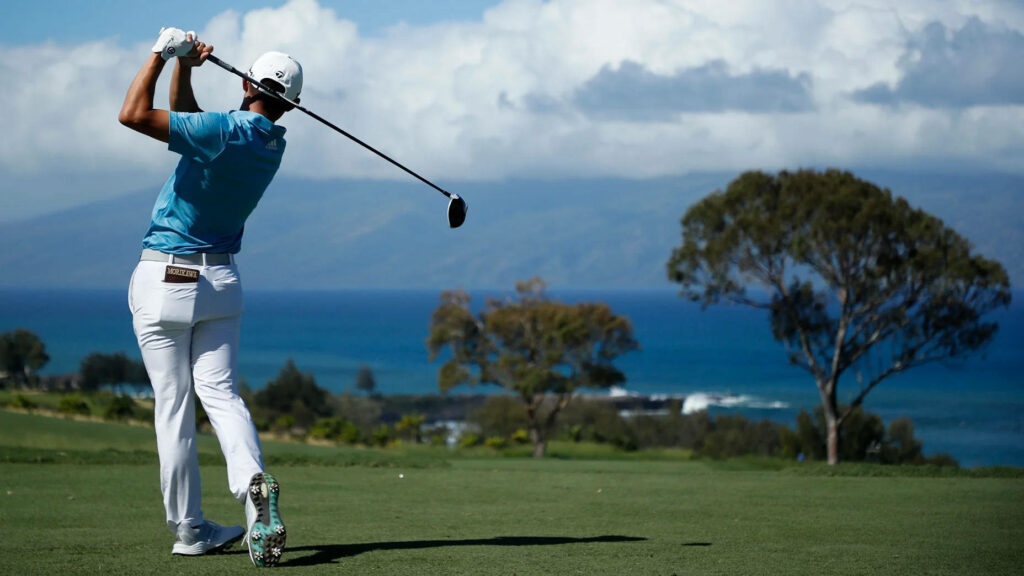 Collin Morikawa golfing on green course with ocean view mountains bright blue sky clouds wallpaper