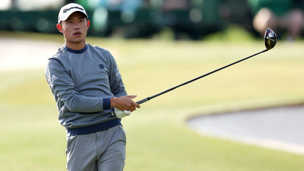 Collin Morikawa golfing wearing grey Adidas sweater and cap with lush green course background Wallpaper