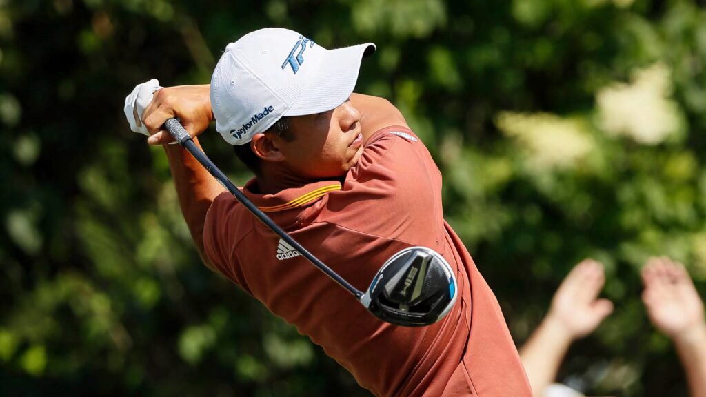 Collin Morikawa mid-swing with TaylorMade club on lush green golf course showcasing athletic form Wallpaper