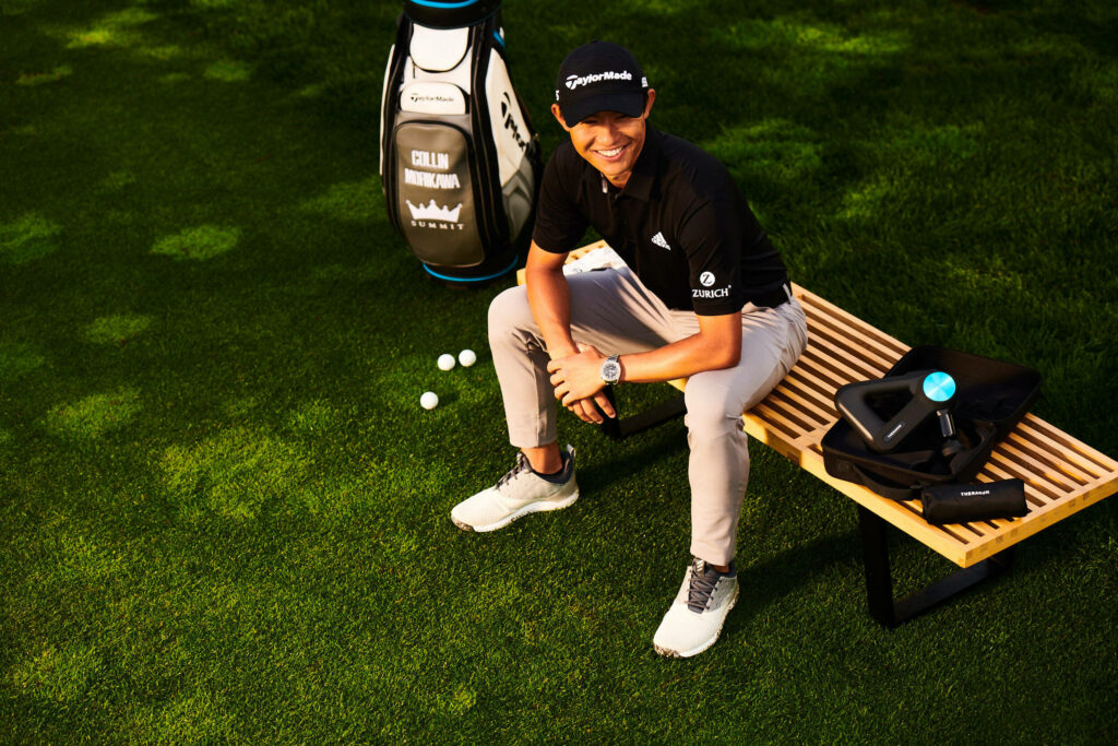 Collin Morikawa sitting on wooden bench smiling in casual golf attire near golf bag outdoors Wallpaper